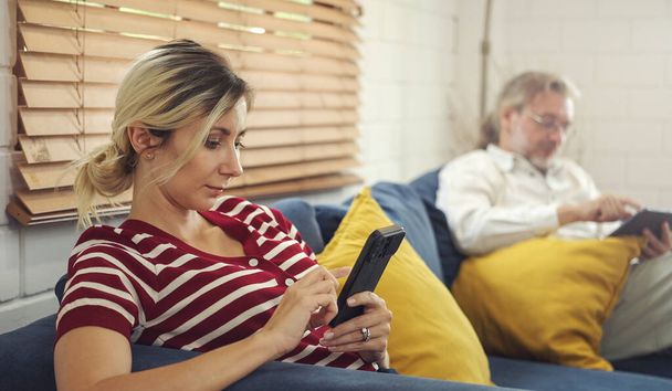 Dipendenza da gadget. padre e padre che tengono e utilizzano diversi dispositivi elettronici mentre sono seduti sul divano in soggiorno a casa. - Foto, immagini