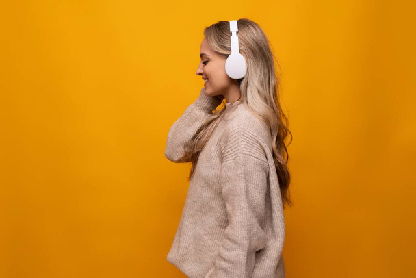 Mädchen lauscht aufmerksam einem Podcast mit Kopfhörern auf gelbem Hintergrund. - Foto, Bild