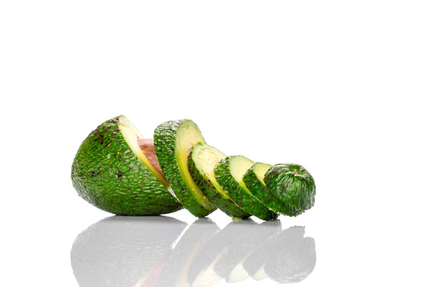 One dark green, delicious, organic avocado, cut across into several pieces, on a white background. - Photo, Image