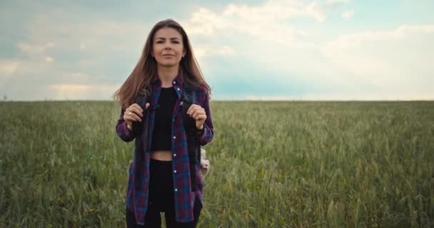 Πορτρέτο μιας όμορφης Καυκάσιας. Ένα κορίτσι ντυμένο με ένα πουκάμισο με ένα σακίδιο στην πλάτη κοιτάζει την κάμερα. Τέχνη, ελευθερία της ένωσης με τη φύση. Υψηλής ποιότητας 4k πλάνα - Πλάνα, βίντεο