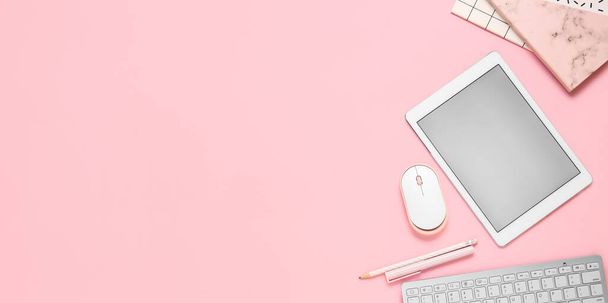 Nowoczesny tablet z klawiaturą, myszką i biurową papeterią na różowym tle z miejscem na tekst - Zdjęcie, obraz