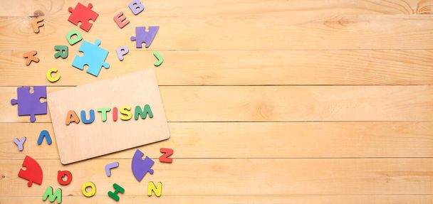 Word AUTISM, letters and puzzle pieces on wooden background with space for text - Valokuva, kuva
