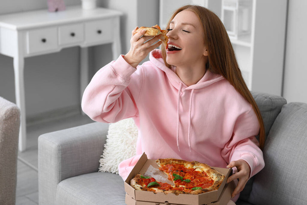 Giovane donna mangiare gustosa pizza sul divano a casa - Foto, immagini