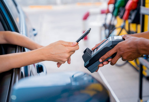 Woman using contactless payment by mobile phone with QR code at car filling station. - Foto, Imagem