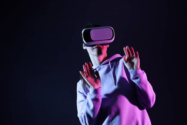 Pretty young woman in VR glasses on black background - Photo, Image