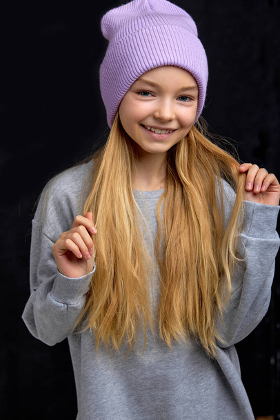 pretty adorable child touching her fair straight hair, isolated black background - Photo, image