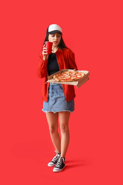 若いです女性ともにおいしいピザとカップ上の赤い背景 - 写真・画像