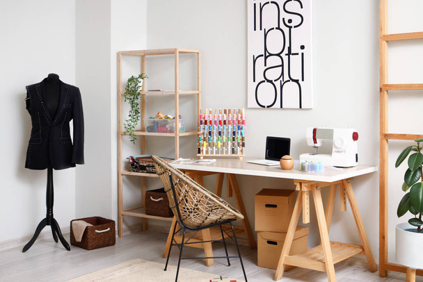 Interior of modern atelier with tailor's workplace, shelving unit and mannequin - Фото, изображение