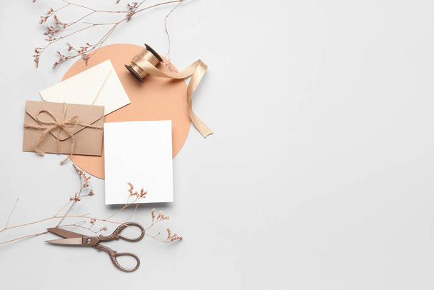 Komposition mit Blanko-Karte, Umschlägen, Schere, Band und getrockneten Blumen auf weißem Hintergrund - Foto, Bild