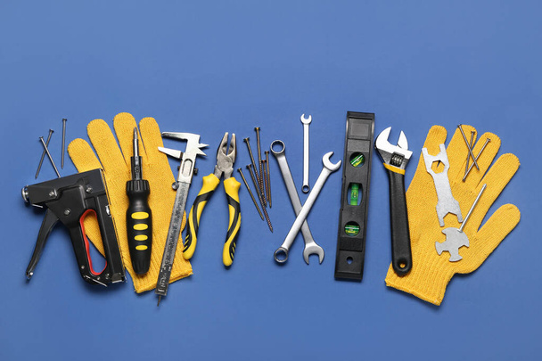 Different construction tools and gloves on blue background - Foto, afbeelding