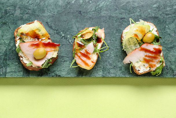 Tábla ízletes szendvicsek krémsajt, sonka és mártással színes háttér, closeup - Fotó, kép