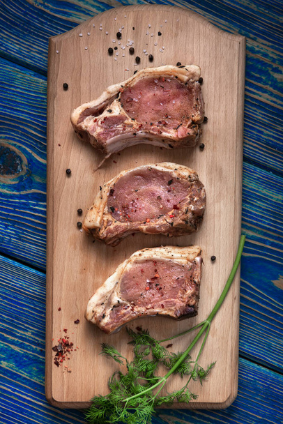 Fresh pork with ingredients for cooking on blue background. top view - Фото, изображение