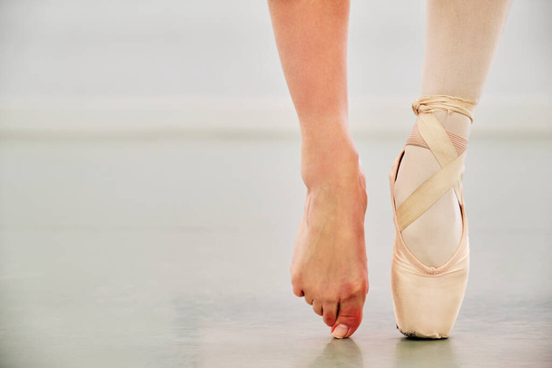 Τραβηγμένη φωτογραφία μιας νεαρής μπαλαρίνας που φοράει ένα μυτερό παπούτσι στο ένα πόδι και τίποτα στο άλλο.. - Φωτογραφία, εικόνα