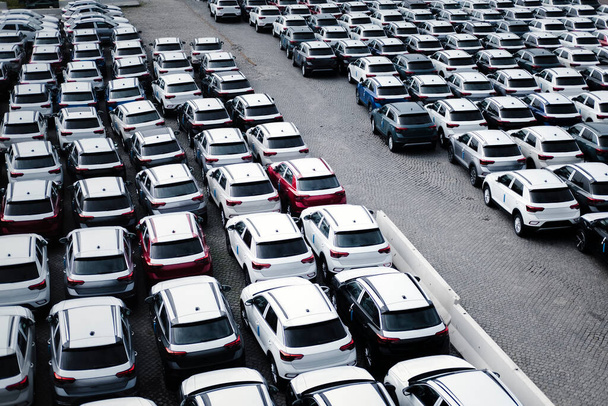 Un estacionamiento con muchos coches nuevos. Una vista aérea de un estacionamiento al aire libre. - Foto, imagen