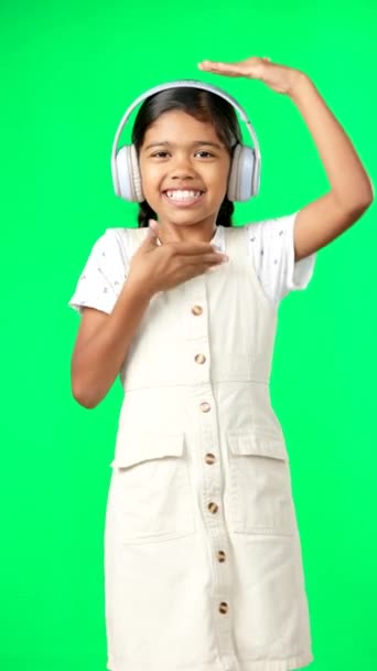 Портрет, музика і танці з дівчиною на фоні зеленого екрану в студійному потоковому аудіо. Діти, посмішка і веселощі з чарівною дівчинкою танцюють під час прослуховування радіо на навушниках
. - Кадри, відео