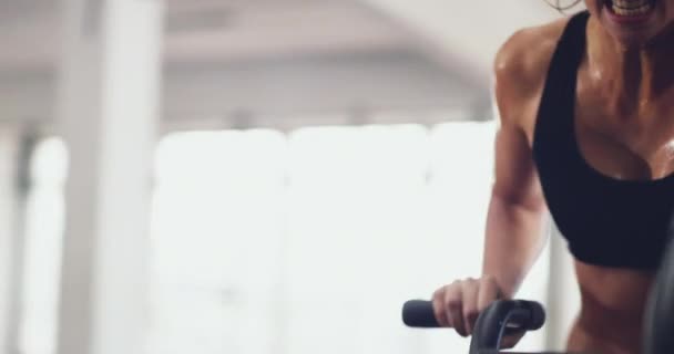 Athletic, fit and active woman sweating at the gym while cycling on an exercise bike. Dedicated and sporty woman doing intense workout on elliptical machine using her membership at fitness facility. - Video