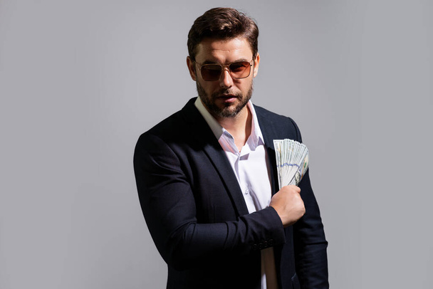Man showing cash money in dollar banknotes. Portrait of business man isolated on gray studio background. Successful winner celebrating success or victory with money bills - Photo, Image