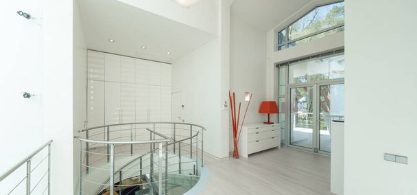 Modern interior of hall in luxury private house. Spiral staircase made of glass and metal. White wardrobe. - Photo, Image