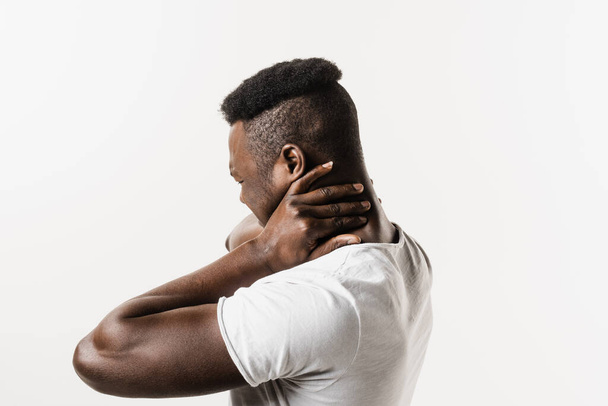 Rachiocampsis bachache e dolore al collo dell'uomo afroamericano su sfondo bianco. La scoliosi è una curvatura laterale della colonna vertebrale. Reumatismi e malattie dell'artrite - Foto, immagini