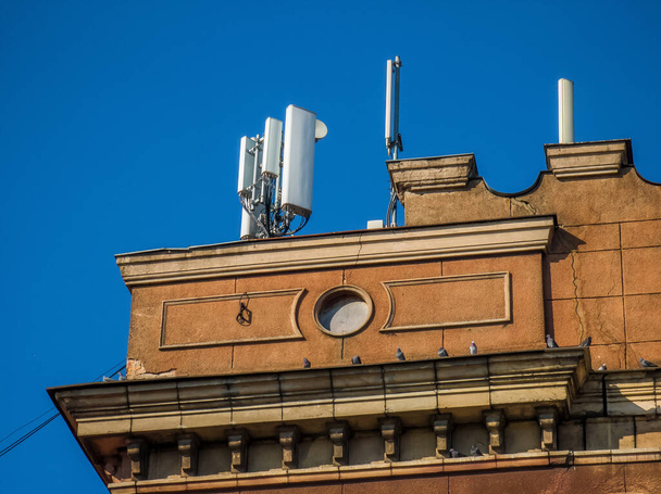 Wireless Communication Antenna on roof of old building. Modern architecture. Blue sky. - Photo, Image