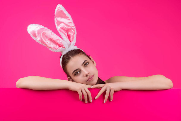 Easter woman. Cheerful young girl celebrating easter isolated over studio background. Studio photo of a young woman wearing bunny ears. Festive bunny - 写真・画像