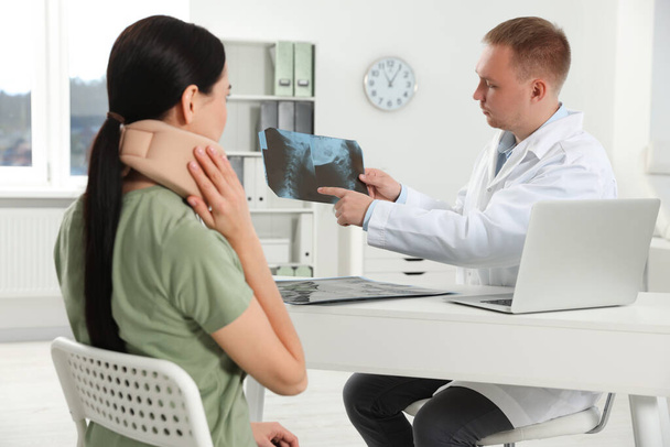 Doctor with neck MRI image consulting patient in clinic - Фото, зображення