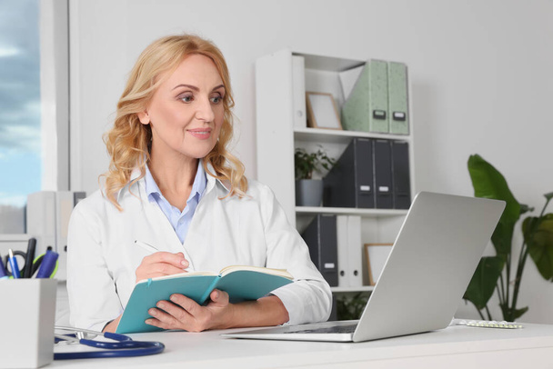 Doctor with laptop consulting patient in clinic. Online medicine concept - Foto, Bild