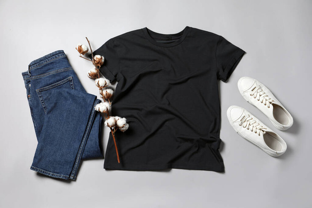 Stylish t-shirt, jeans and sneakers on light grey background, flat lay - Valokuva, kuva