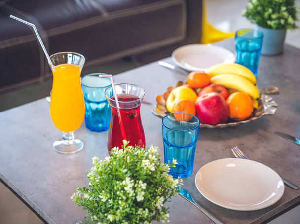 Close-up of table. Leather sofas. Plates and glasses. Fruits on plate. Cocktails. Interior of private house. - Foto, Bild