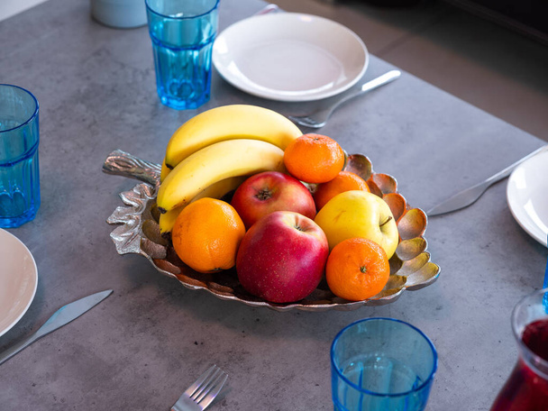 Close-up of fruits in bowl in shape of leaf on the table. Apples, oranges, bananas. Healthy food. - Fotó, kép