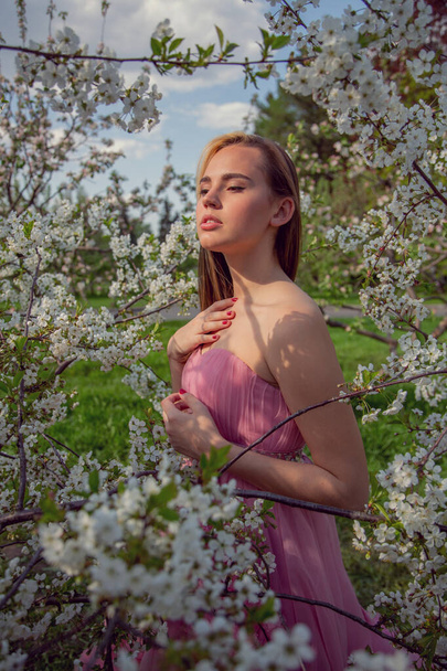 Portrait of an Asian girl in a beautiful evening dress in a blooming garden. Flowering trees, Japanese Hanami Sakura Festival travel, seasonal. - 写真・画像