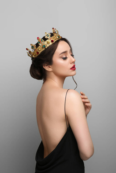 Beautiful young woman wearing luxurious crown on light grey background - Foto, afbeelding