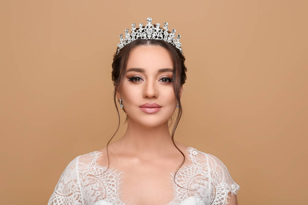 Beautiful young woman wearing luxurious tiara on beige background - Foto, Imagen
