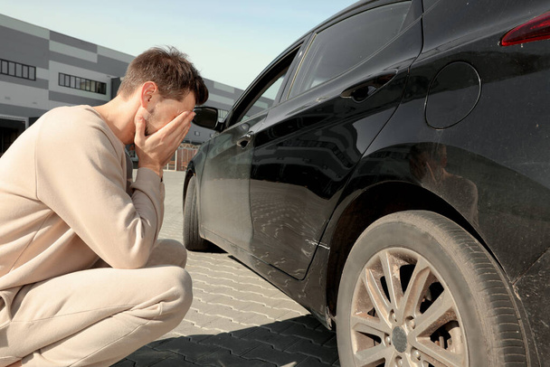 Stressed man near car with scratch outdoors - Foto, afbeelding