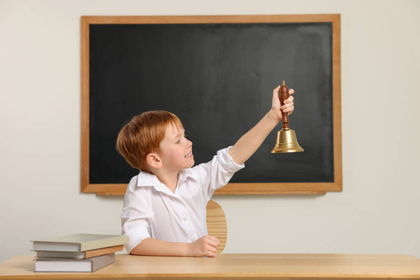 Cute little boy ringing school bell in classroom - Fotografie, Obrázek