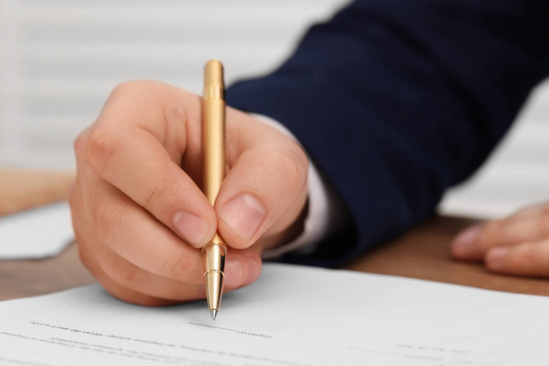 Man signing document at table, closeup view - Фото, изображение