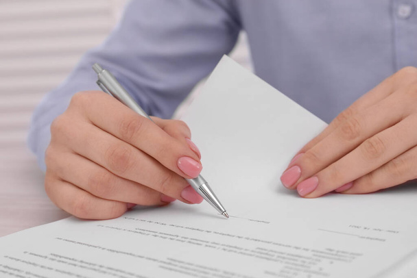 Woman signing document at table, closeup view - Foto, Bild