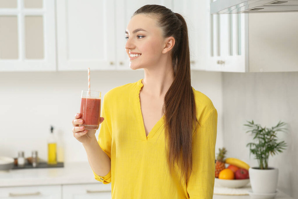 Beautiful young woman with delicious smoothie in kitchen - Fotoğraf, Görsel