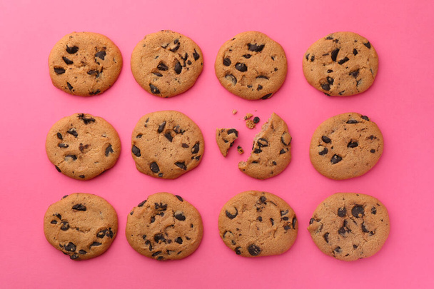 Many delicious chocolate chip cookies on pink background, flat lay - Foto, imagen