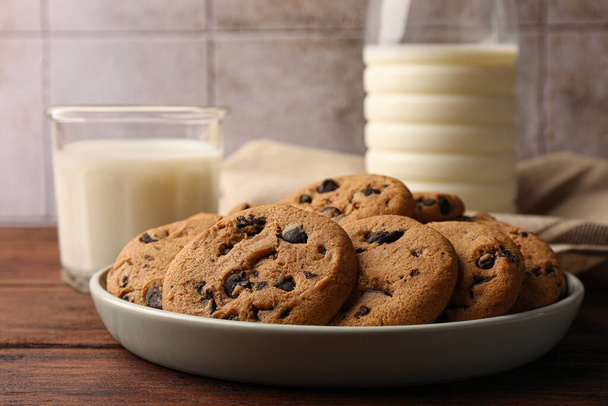 Delicious chocolate chip cookies and milk on wooden table, closeup - Fotoğraf, Görsel