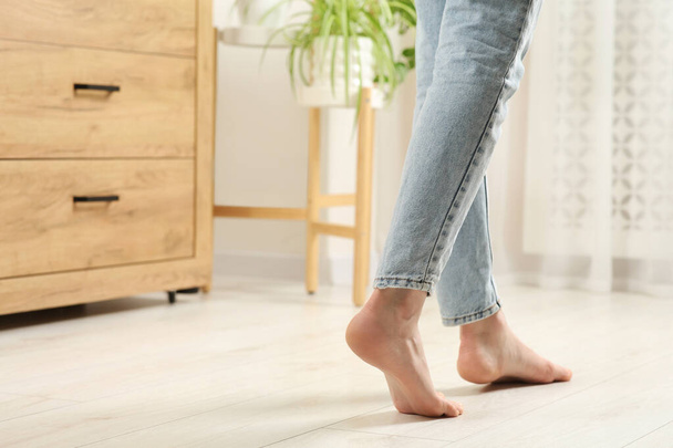 Woman stepping barefoot in room at home, closeup with space for text. Floor heating - Foto, imagen