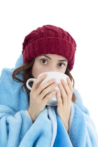 Woman warming herself under a blanket and with a cup of tea - Foto, immagini