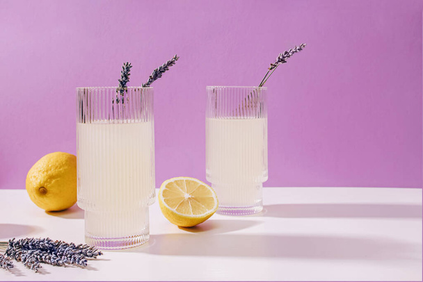 Két bordás pohár levendulás limonádéval lila háttérrel, nyári frissítő ital. - Fotó, kép