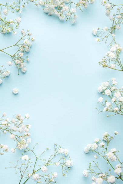 Białe cygańskie kwiaty lub kwiaty oddechu dziecka na niebieskim tle. Przestrzeń kopiowania. - Zdjęcie, obraz