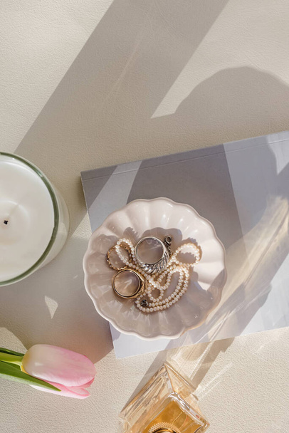 Flat lay with jewelry in a small plate, tulip and other items in natural light - Valokuva, kuva