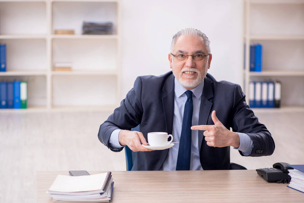Old employee drinking tea at workplace - Zdjęcie, obraz
