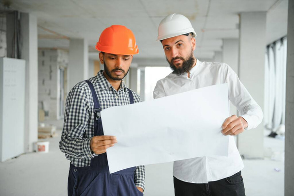 Young attractive arabic industrial engineer in hard hat. Professional and industry, builder architect job, worker checking work at plant indoor. - Фото, изображение