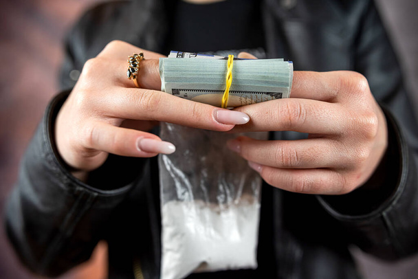 Kobieta nosi czarny materiał trzymać dolara i dawkę kokainy lub heroiny. Koncepcja uzależnienia od narkotyków. Przedawkowanie - Zdjęcie, obraz