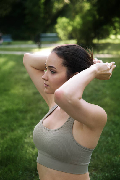 Portrait of a slender girl. A beautiful young woman is preparing for yoga or sports in the park. The concept of a healthy lifestyle and life extension - 写真・画像