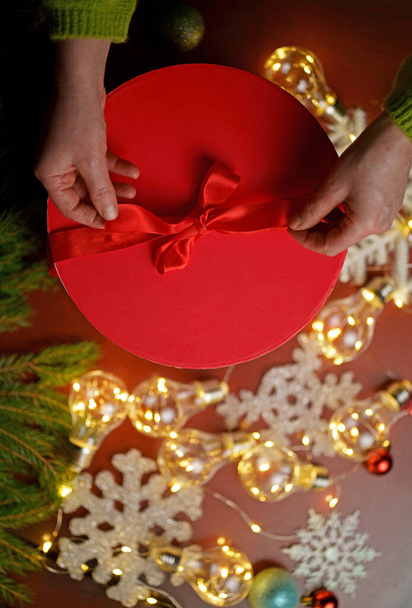Woman holding christmas gifts laid on wooden table background with christmas decoration - 写真・画像